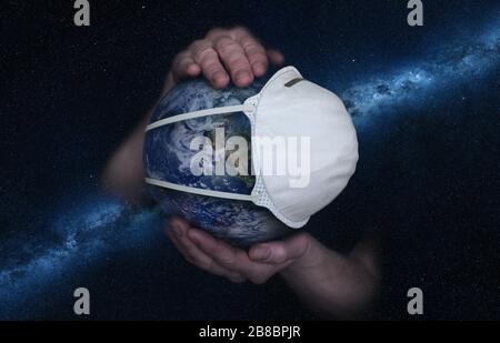 Female hands hold the Earth in a medical protective mask against the starry sky during the epidemic Covid19 or coronavirus. Concept Stock Photo