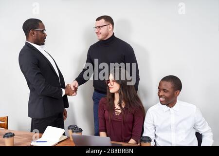 Young happy business people working together in modern office, multiethnic teamwork. Greeting with handshake  Stock Photo