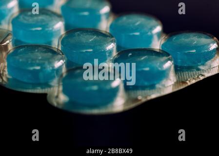 Blue coated tablets in blister packaging on the black background Stock Photo