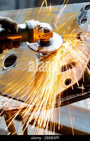 A worker using a grinder cut metal. Processing a metal product using a manual grinder. Stock Photo