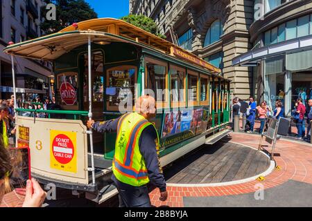 Operator turning a cable car around in the reverse direction at the Powell and Market Street Turntable in San Francisco USA