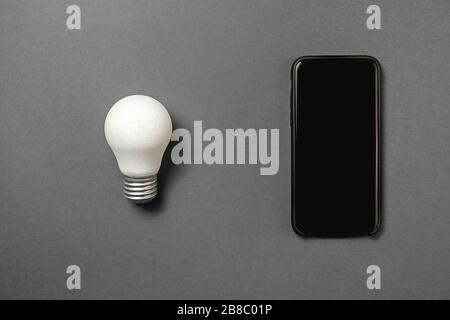 Concept for saving energy, eco-friendly, global warming. Creative top view flat lay of LED light bulb and modern phone mockup composition with copy sp Stock Photo