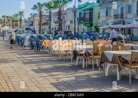 Empty tables of street restaurants on boardwalk in Malta during covid-19 coronavirus quarantine: Marsaxlokk, Malta - 29 June, 2018 Stock Photo