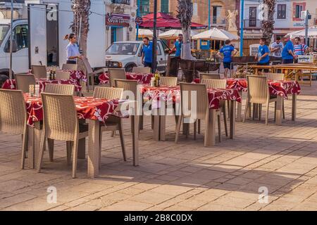 Empty tables of street restaurants on boardwalk in Malta during covid-19 coronavirus quarantine: Marsaxlokk, Malta - 29 June, 2018 Stock Photo