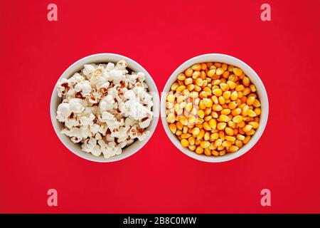 Two bowls filled with popcorn and corn maize or kernel seed on red background. Popcorn preparation. Stock Photo