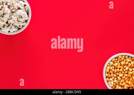 Two bowls filled with popcorn and corn maize or kernel seed. on red background with copy space. Popcorn preparation. Stock Photo