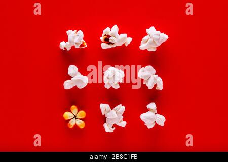 Popcorn and corn kernels in a row on red background. Popcorn preparation Stock Photo
