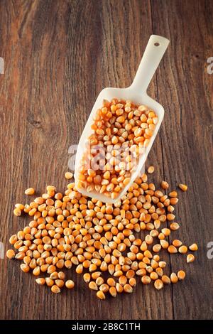 Corn maize or kernel spill out from a scoop on wooden kitchen table Stock Photo