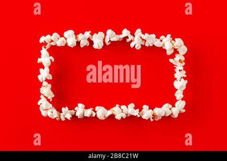 Blank frame made of popcorn on red background with copy space. Stock Photo