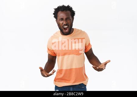 Masculine and sassy, confident young serious-looking african american guy acting manly and harsh, shouting to act cool, spread hands sideways, yelling Stock Photo
