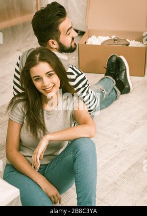 Happy man and woman sitting on the floor tired preparing to relocate to new apartment Stock Photo