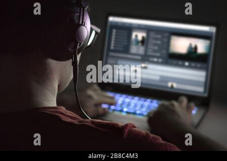 Video editing with laptop. Professional editor adding special effects or color grading footage. Back view of young man using computer software. Stock Photo