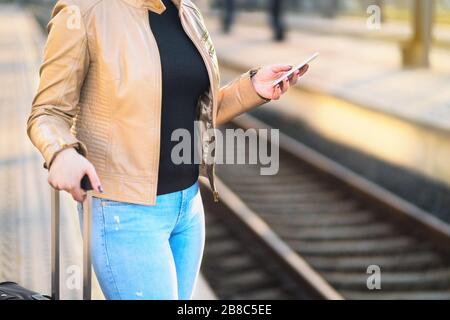 Commuter using smartphone in train station. Woman buying electronic ticket with mobile phone in platform. Commute, transportation and technology. Stock Photo