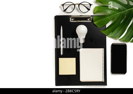 Concept brainstorming. Creative top view flat lay of desk with clipboard, pen, monstera leaves, eyeglasses, notebook, modern smartphone composition wi Stock Photo