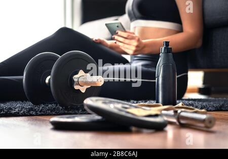 Working out at home with online fitness course, workout video or personal trainer service in phone. Health or sport mobile app in cellphone. Stock Photo