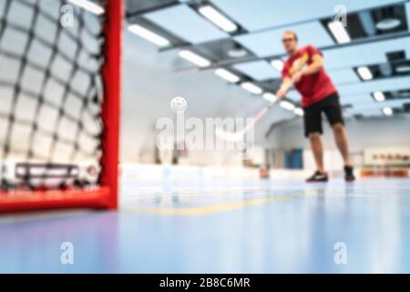 Floorball training on court. Man training floor hockey in arena. Slap shot on goal. Stock Photo