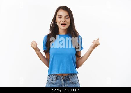 Yeah I did it. Satisfied triumphing brunette girl excited over successful work, got approval, clench fists in victory, smiling powerful and upbeat Stock Photo