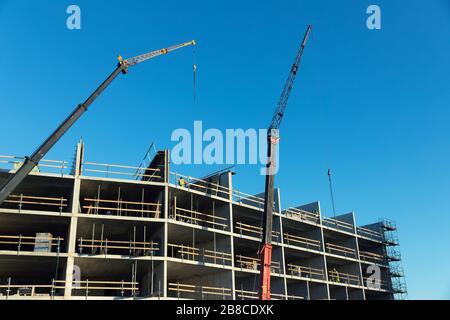 housing development - workers and cranes working on apartment building construction site Stock Photo