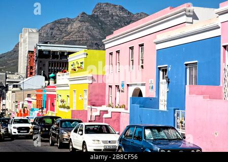 View down the brightly coloured facades of the houses of Wale Street to Buitengracht Street. Across the traffic and buildings, Devil's Peak looks down. Stock Photo