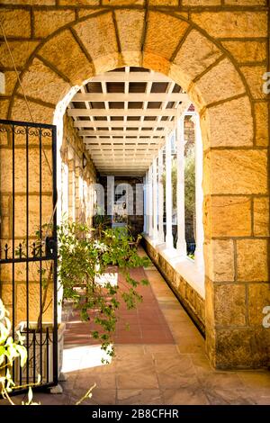 View through the gated archway, along the peaceful colonnade leading to the entrance of the chapel at Nazareth House. Stock Photo