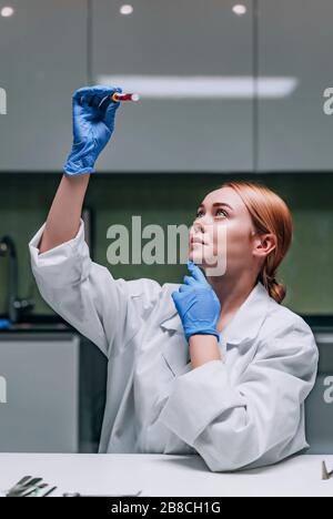 Female medical or scientific researcher looking at a test tube in a laboratory. Stock Photo