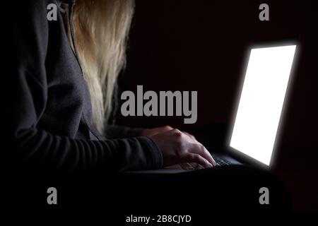 Overhead hacker in the hood working with laptop typing text in the darkroom.  Stock Photo