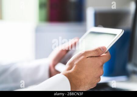 Doctor and medical professional using tablet at work in health care. Physician using digital electronic mobile device. Patient database online. Stock Photo