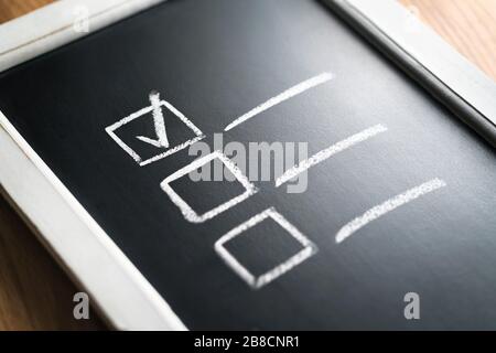 Checklist on chalkboard. Agenda and progress of project in business. Document of finished work duties and responsibilities. Stock Photo