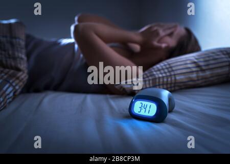 Sleepless woman suffering from insomnia, sleep apnea or stress. Tired and exhausted lady. Headache or migraine. Awake in the middle of the night. Stock Photo