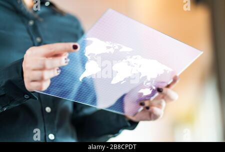 Modern global and international business technology concept. Businesswoman using futuristic transparent tablet with world map on screen. Stock Photo