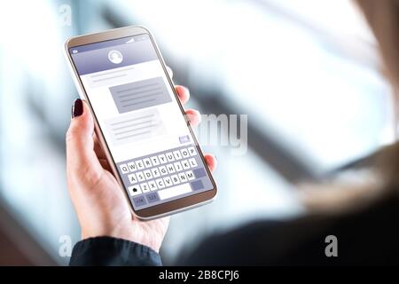 Woman sending text messages with mobile phone. Cellphone in hand with sms application on screen. Person using instant messaging software. Stock Photo