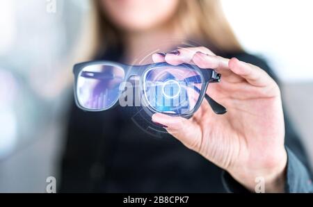 Virtual screen smart glasses with futuristic high tech interface. Woman holding spectacles with nanotech interface. Augmented reality vision. Stock Photo