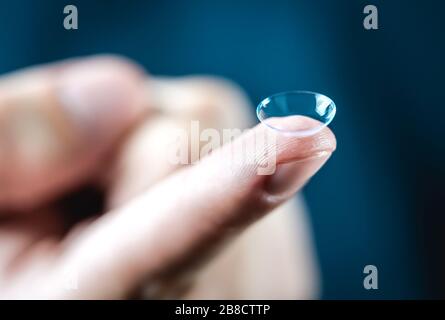 Contact lenses macro close up. Man holding lens on finger. Customer, patient or eye doctor, oculist or optician in clinic. Myopia, eye sight. Stock Photo