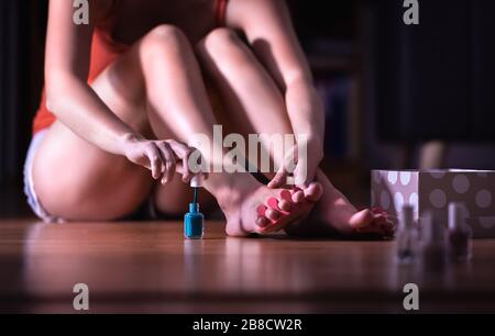 Pedicure at home. Young woman painting toe nails with nail polish. Girl using brush to apply paint to toenails. Stock Photo