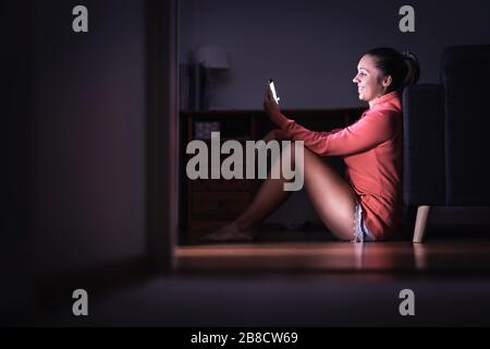 Woman reading texts with smartphone at night. Smiling person using mobile phone. Happy lady dating and flirting. Gossip with friend. New relationship. Stock Photo