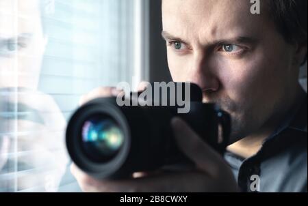 Private detective, undercover cop, investigator, spy or paparazzi with camera taking photos. Agent or police spying, investigating or following people. Stock Photo