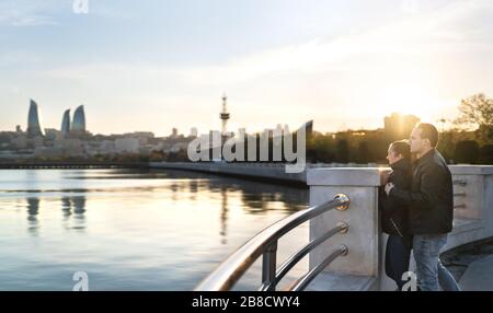 Couple in Baku at sunset looking at the sea. People on a holiday getaway. Happy man and woman on a date. Travel and tourism in Azerbaijan. Stock Photo