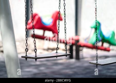 Empty swing at a playground. Sad dramatic mood for negative themes such as bullying at school, child abuse, pedophilia, traumatic childhood or kidnap. Stock Photo