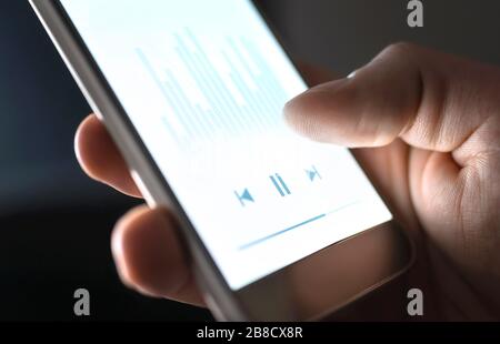 Listening to podcast, music or audiobook with mobile phone. Man using streaming service and smartphone app with audio player and equalizer. Stock Photo