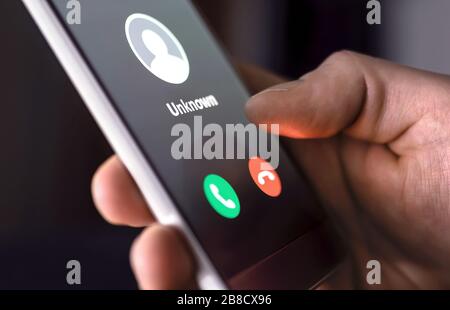 Phone call from unknown number late at night. Scam, fraud or phishing with smartphone concept. Prank caller, scammer or stranger. Man answering. Stock Photo