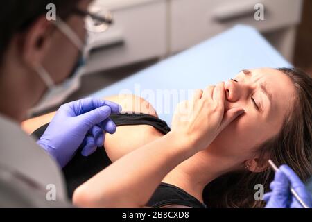 Upset patient having panic attack. Afraid of dentist or fear of doctor. Nervous woman covering mouth. Malpractice or wrong medical treatment. Stock Photo