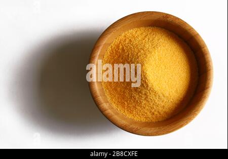 Maize flour in a wooden bowl isolated on white background. Top view. Stock Photo