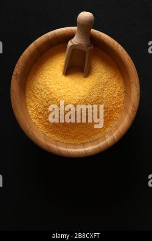 Maize flour in a wooden bowl isolated on dark background. Top view. Stock Photo