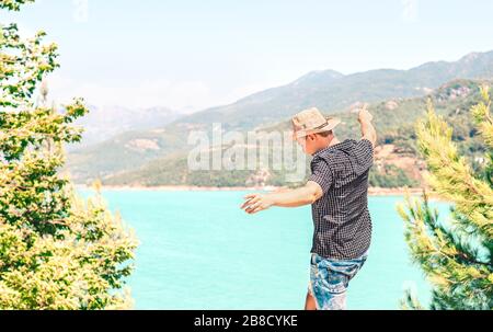Happy man spreading arms and enjoying life in the mountain. Carefree guy with cowboy style hat feeling free. Journey to success. Freedom and fun. Stock Photo