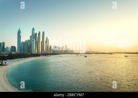 Dubai Marina at sunset. Panorama view of skyscraper buildings, beach, clear sky and sea at dawn. Scenic luxury city skyline in United Arab Emirates. Stock Photo