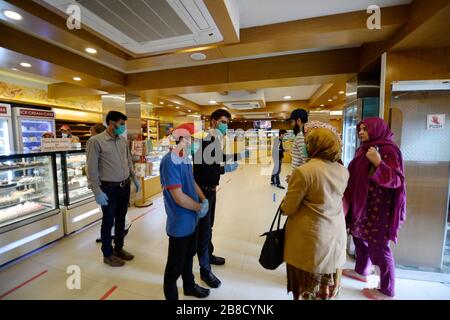 Islamabad, Pakistan. 21st Mar, 2020. Employees wearing masks guide customers to follow the tape marks on the floor as authorities called for social distancing amid concerns over the spread of novel coronavirus at a bakery in Islamabad, capital of Pakistan on March 21, 2020. According to the government statistics, the number of confirmed coronavirus patients rose to 534 in Pakistan on Saturday. Credit: Ahmad Kamal/Xinhua/Alamy Live News Stock Photo