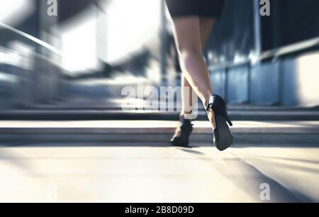 Woman running away or walking fast with high heels in city street. Busy business person in hurry. Late from work or stress fast. Sprint stairs. Stock Photo