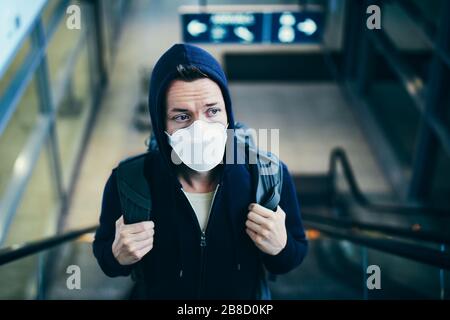 Man wearing face mask on escalator. Themes coronavirus and personal protection during pandemic. Stock Photo