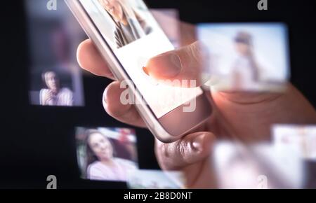 Online dating app or site in mobile phone. Finding love and romance from internet with smartphone. Man giving like. Many hologram photos. Stock Photo