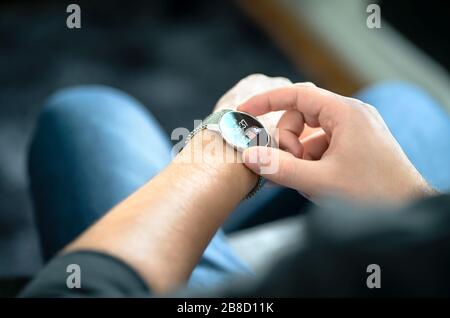Smart watch, wearable gadget. Man wearing hybrid smartwatch. Wearables with digital touchscreen and mobile app technology. Person using wristwatch. Stock Photo